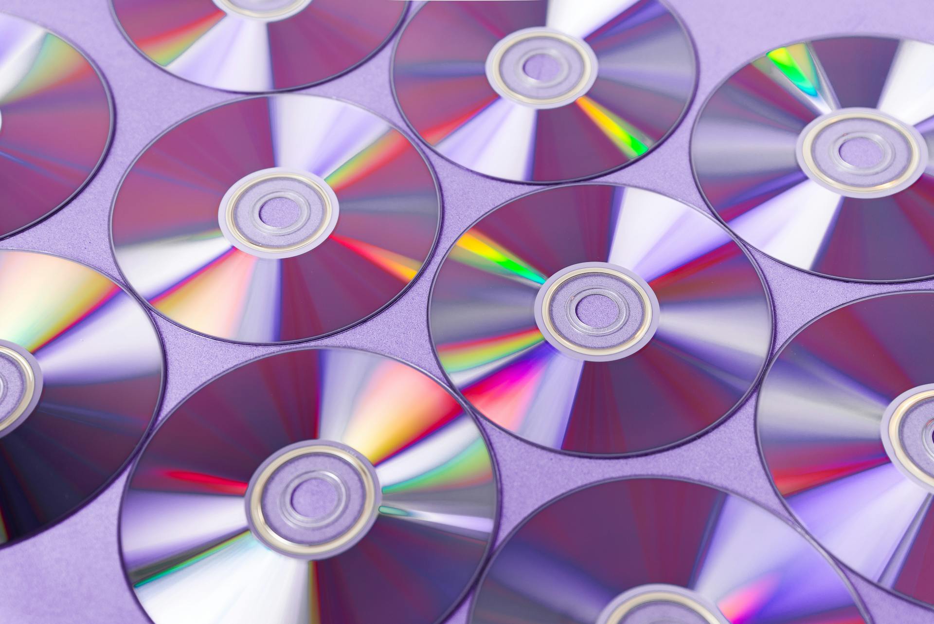 A vibrant arrangement of overlapping CDs reflecting colorful light patterns.