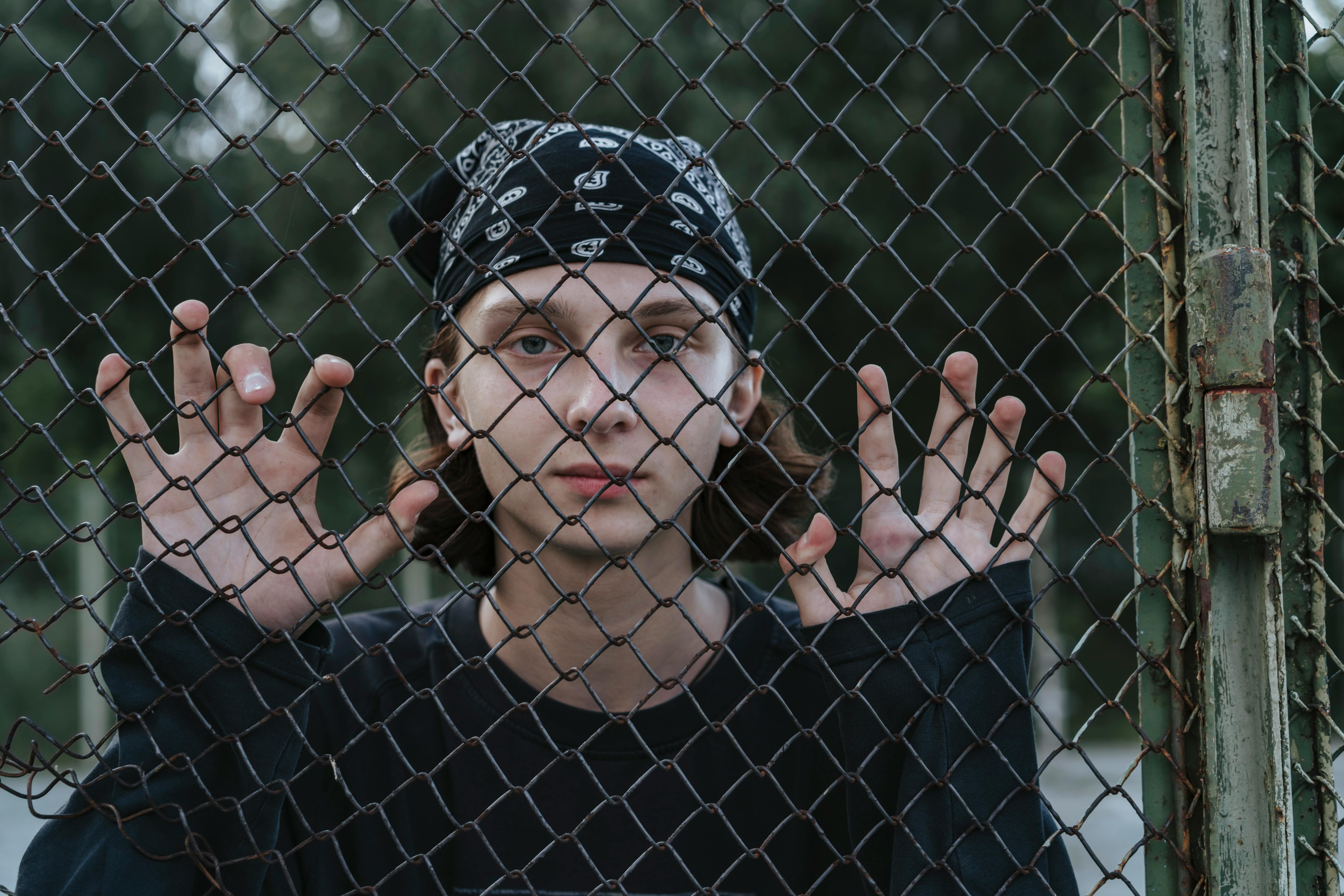 young boy wearing a bandana behind the fence