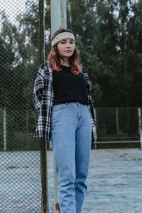 Young Woman Leaning against Goal Net · Free Stock Photo