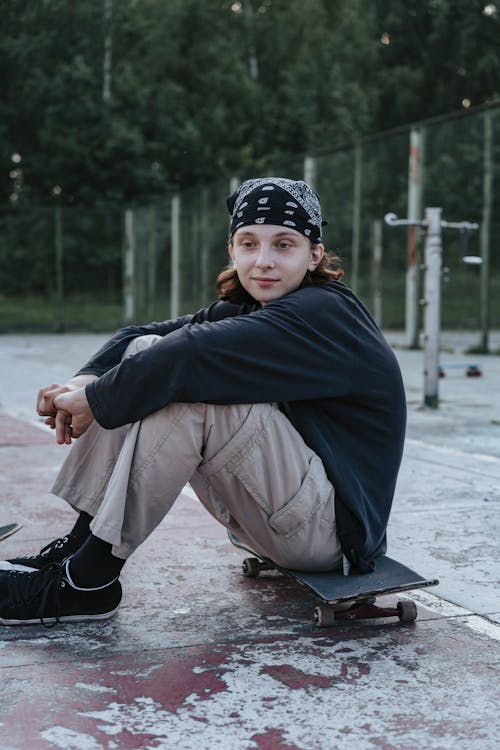 Young Boy Sitting on Black Skateboard