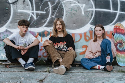 Teenagers Sitting on Gray Concrete Pavement