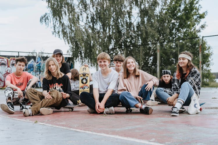 Group Of Teenagers Sitting On Concrete Pavement