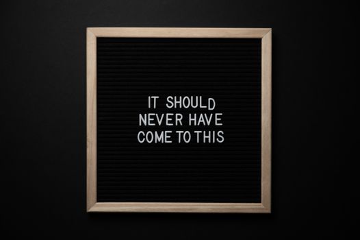 Top view of blackboard with IT SHOULD NEVER HAVE COME TO THIS inscription on black background