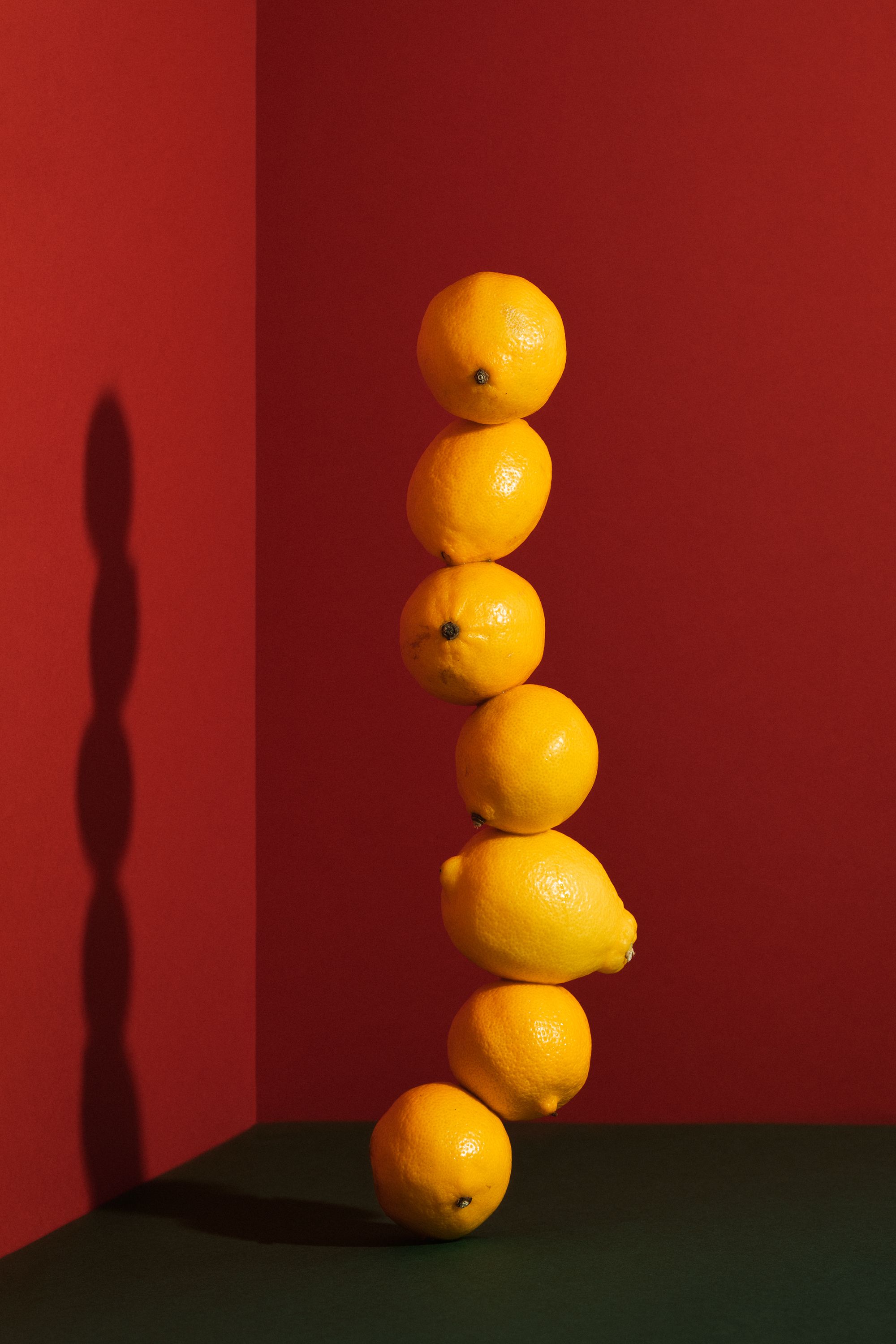 A vertical stack of lemons creatively balanced against a red backdrop, capturing a vibrant and fresh visual.