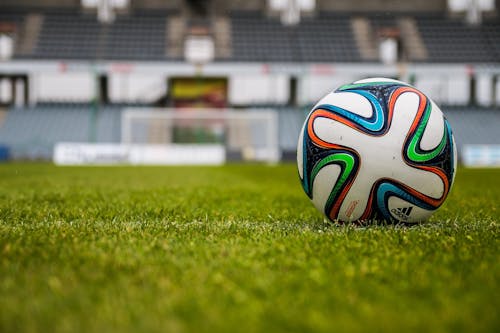 бесплатная футбольный мяч Adidas синий оранжевый черный зеленый белый на зеленом поле Стоковое фото