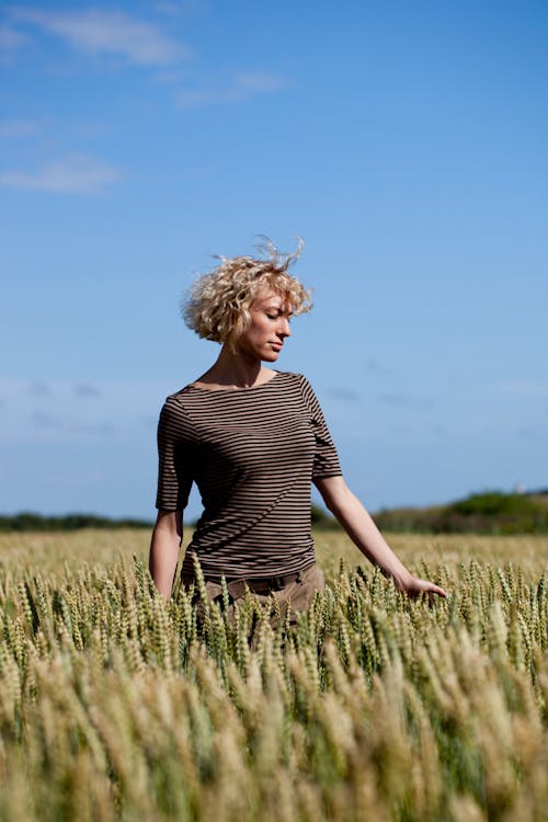 Woman in Black and Brown Striped Shirt Standing on the Wheat Field