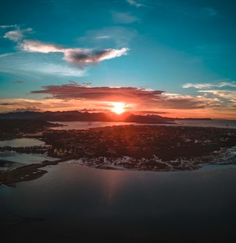 High view of peninsula with town surrounded water against mountains at colorful sunset