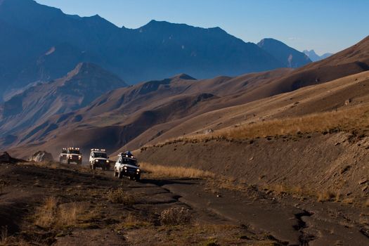 Jeeps navigate dusty mountain trails during an off-road adventure at dusk.
