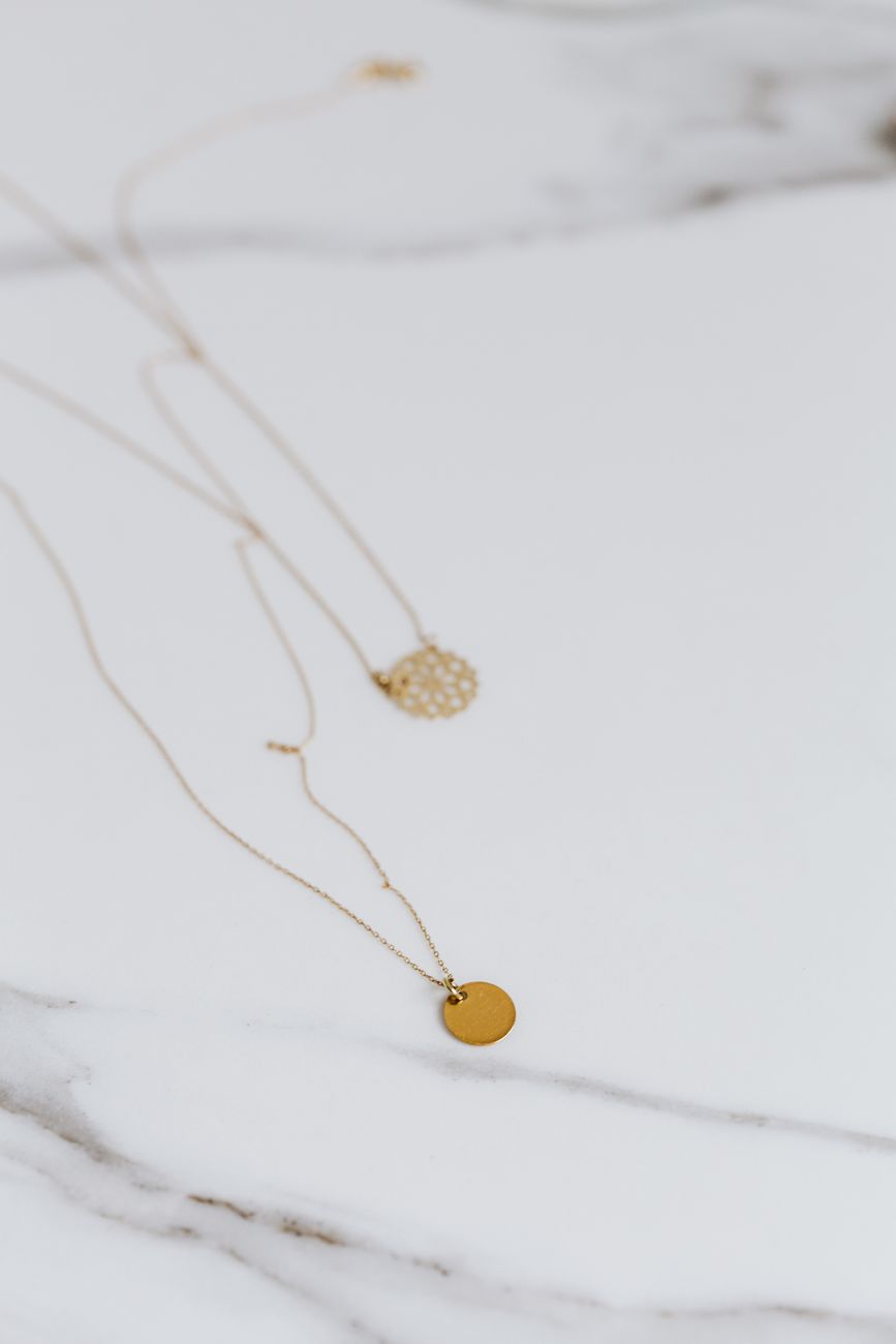 Gold pendant necklaces arranged on a marble surface
