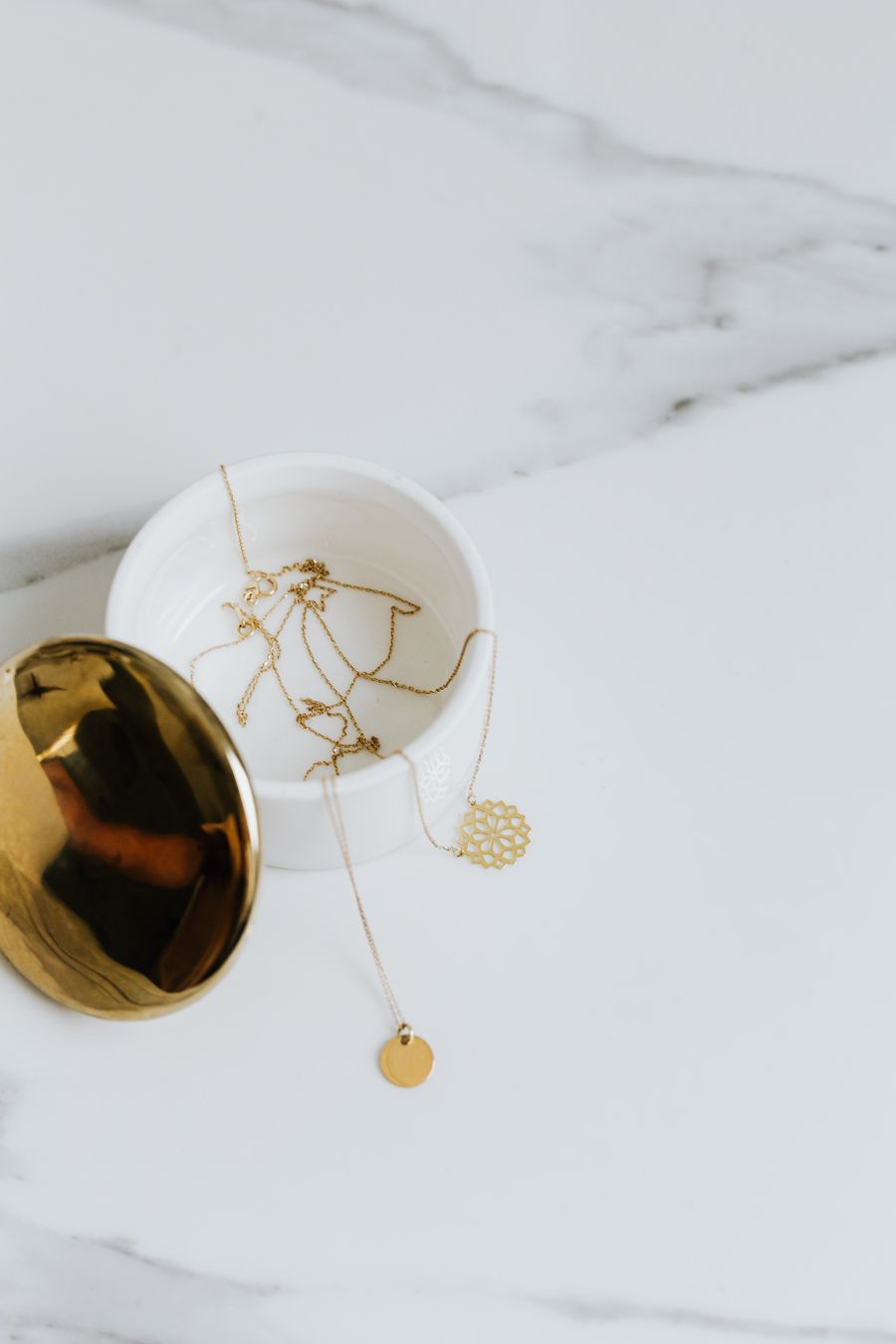 Gold necklaces and pendants in a white marble container