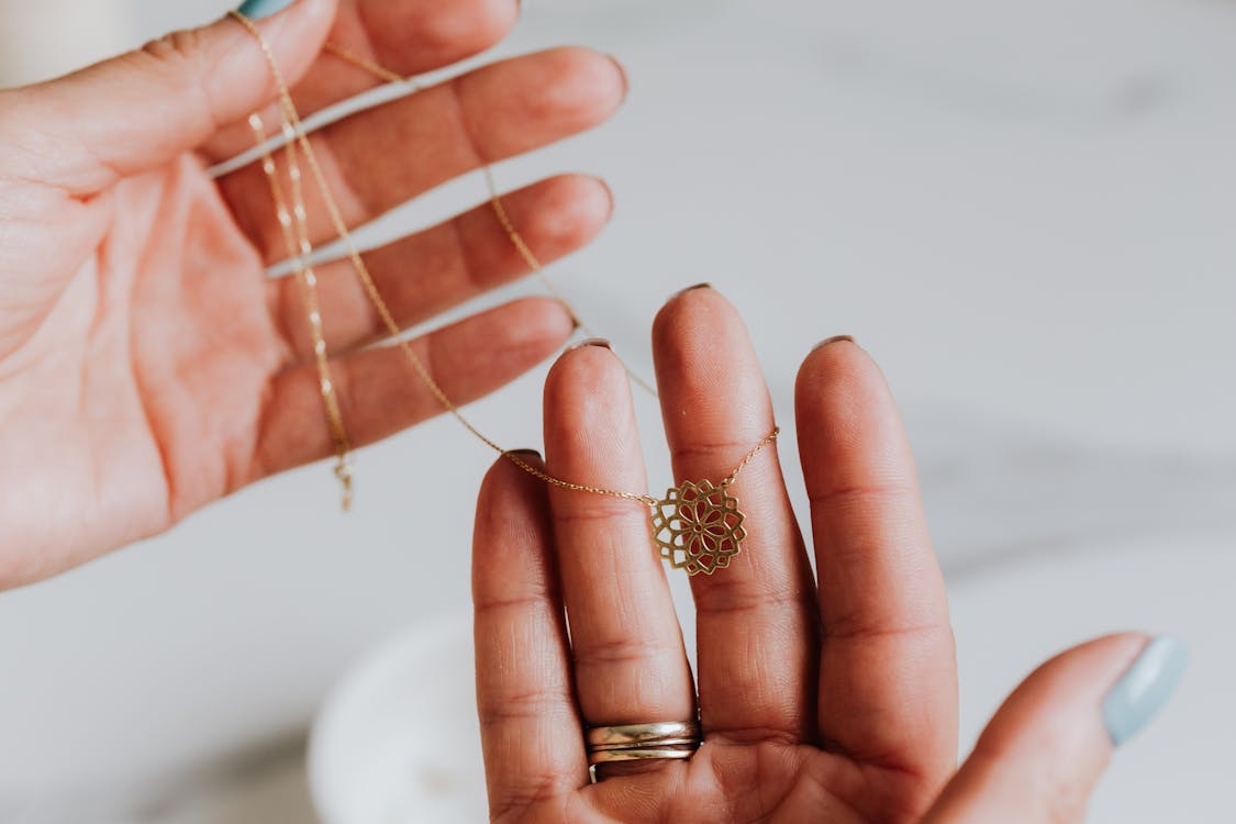 Free Gold Necklace with Flower Pendant on Human Fingers Stock Photo