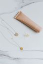Stylish arrangement of gold jewelry and a cosmetics tube on a marble surface, ideal for elegant branding.