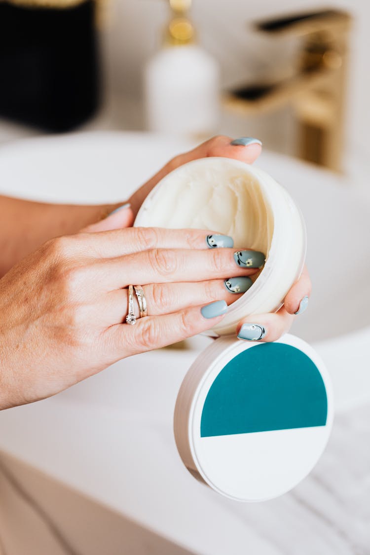 Fingers On Round White Container With White Cream