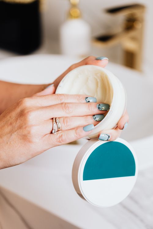 Free Close-up of hands applying skincare cream from a round container, showcasing elegant nail art. Stock Photo