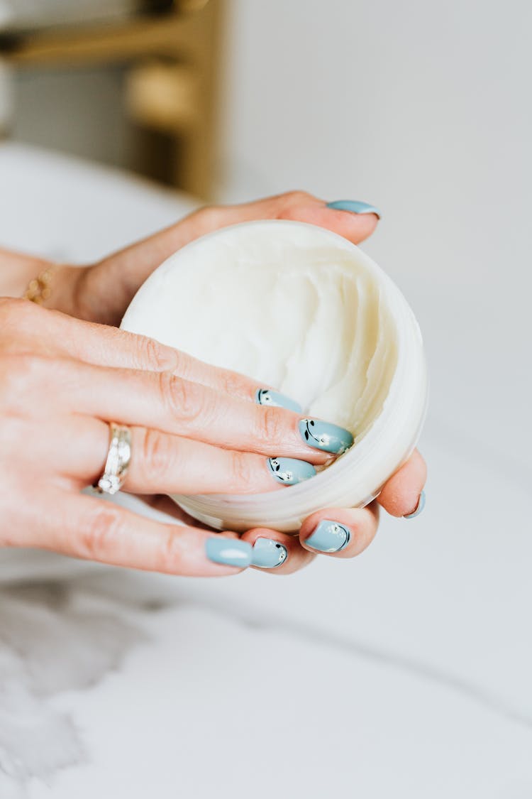 Fingers On White Round Container With Cream