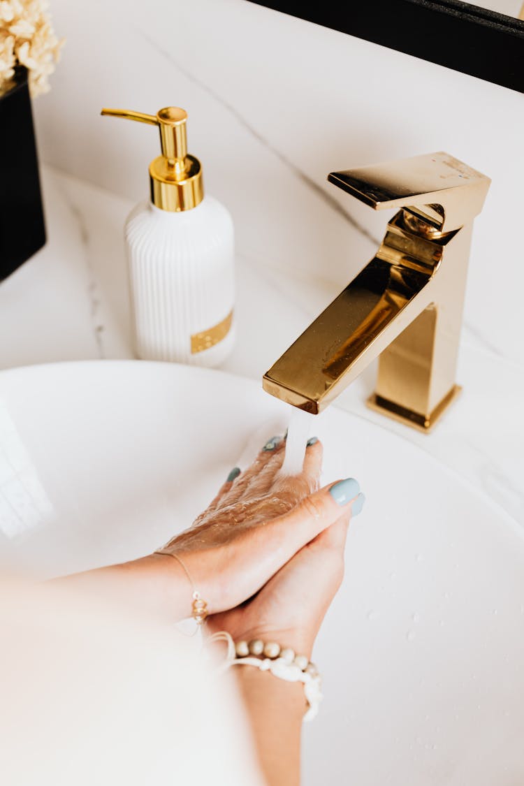 Person Washing Hands On A Sink With Pump Bottle Soap