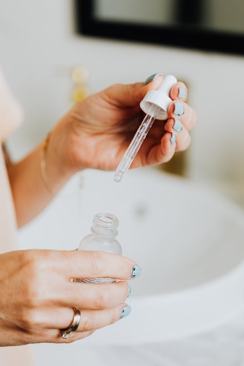 Free Close-up of Woman Holding a Serum in a Glass Bottle and a Pipette  Stock Photo