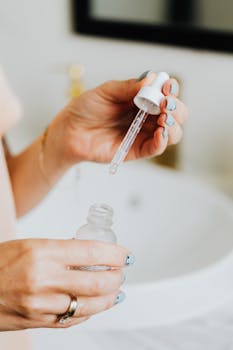 A woman applying skincare serum with a glass pipette in an indoor setting.