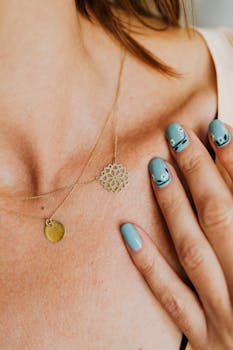 特写镜头中，一条金项链搭配优雅美甲，色调柔和呈蓝色