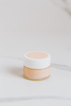 A sleek glass cosmetic jar on a pristine white marble background, ideal for skincare branding.