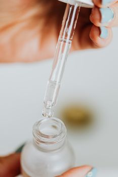 日常护肤中，点滴器将液体分配到玻璃精华瓶的详细特写