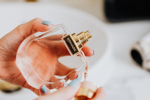 Free Hand Holding a Clear Glass Bottle of Perfume Stock Photo