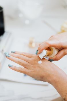一位女士正用泵式分配器取护肤霜进行自我护理的特写