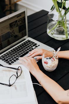 Woman working on laptop with a healthy oatmeal and berry snack, creating a balanced work-life atmosphere.