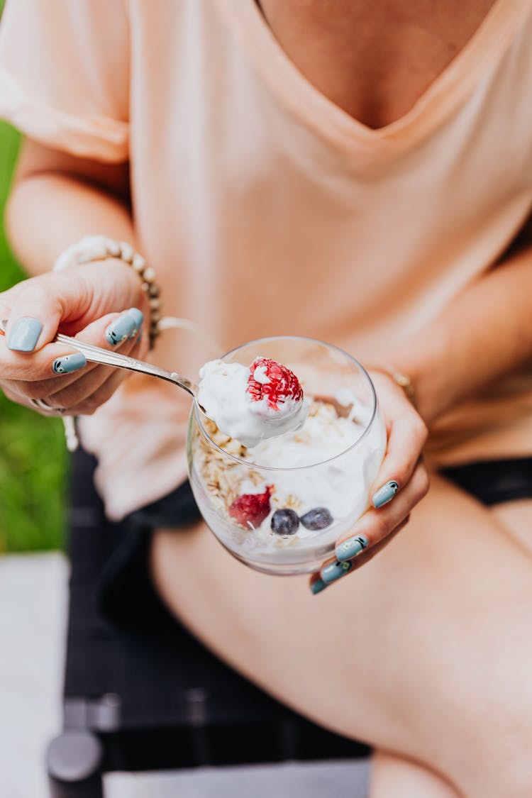 Close-up Of Woman Eating Yogurt With Granola And Fruit 