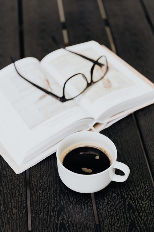 Free Open book with eyeglasses and coffee cup on a wooden table, perfect for a cozy reading session. Stock Photo