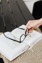 Person Holding Black Framed Eyeglasses on White Book Page