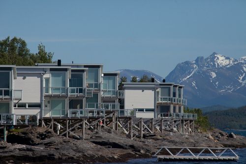 Free Contemporary lakeside cabins with stunning mountain backdrop, perfect for serenity seekers. Stock Photo