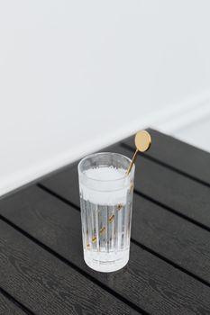 一杯加冰的时尚鸡尾酒，置于深色木桌上，配有一支金色搅拌器
