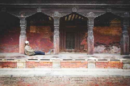 Free A man casually sitting by historic columns of a temple in Kathmandu, Nepal. Stock Photo