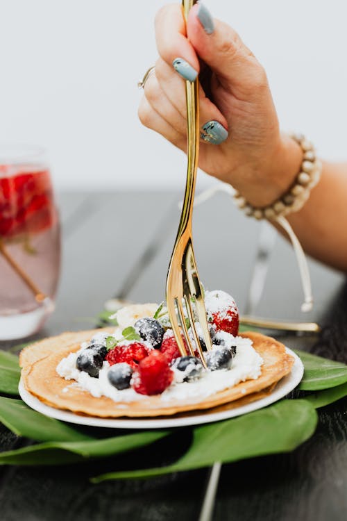 Person Eating Pancakes with Fresh Fruits