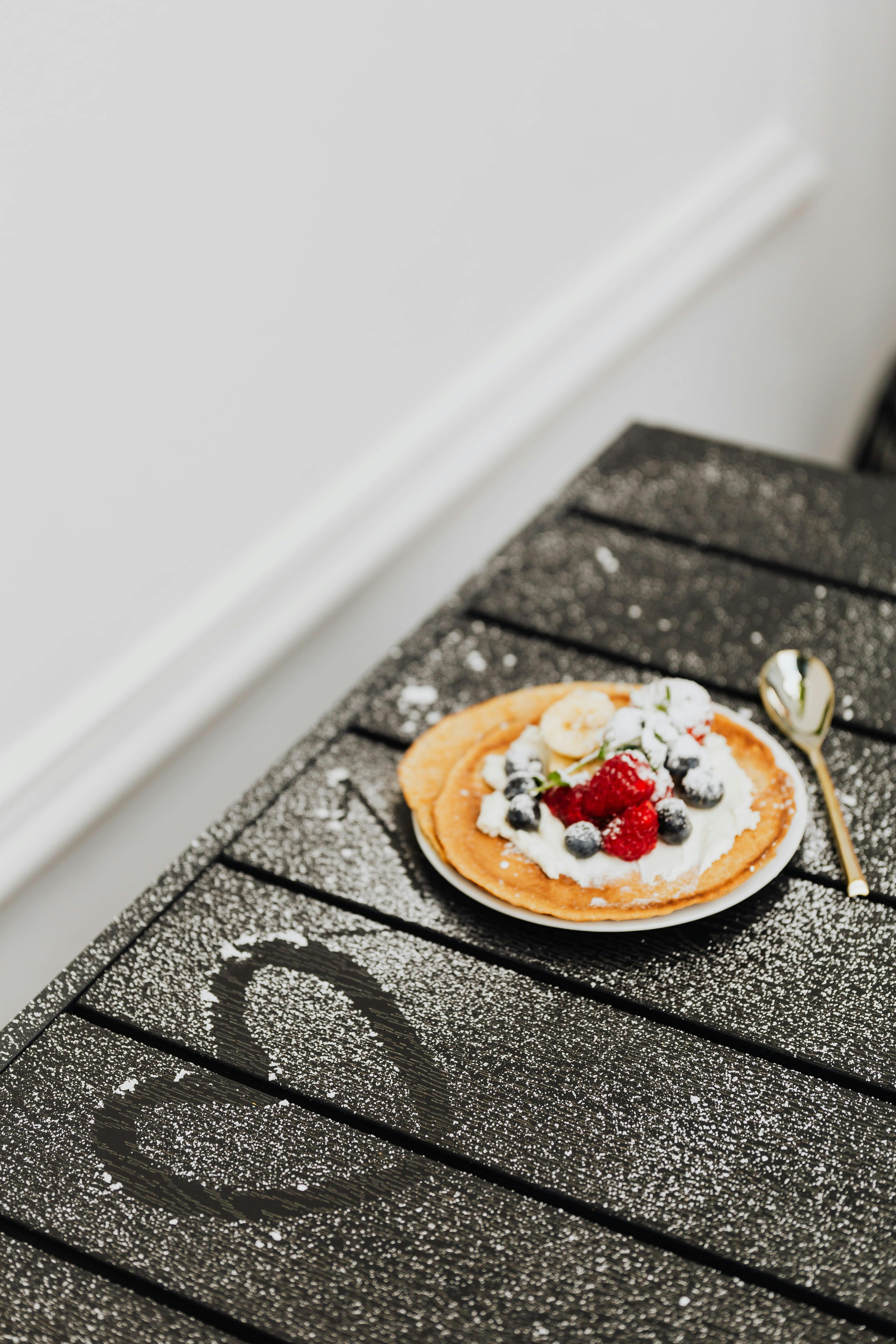 pancakes with fruits topping over a wooden table