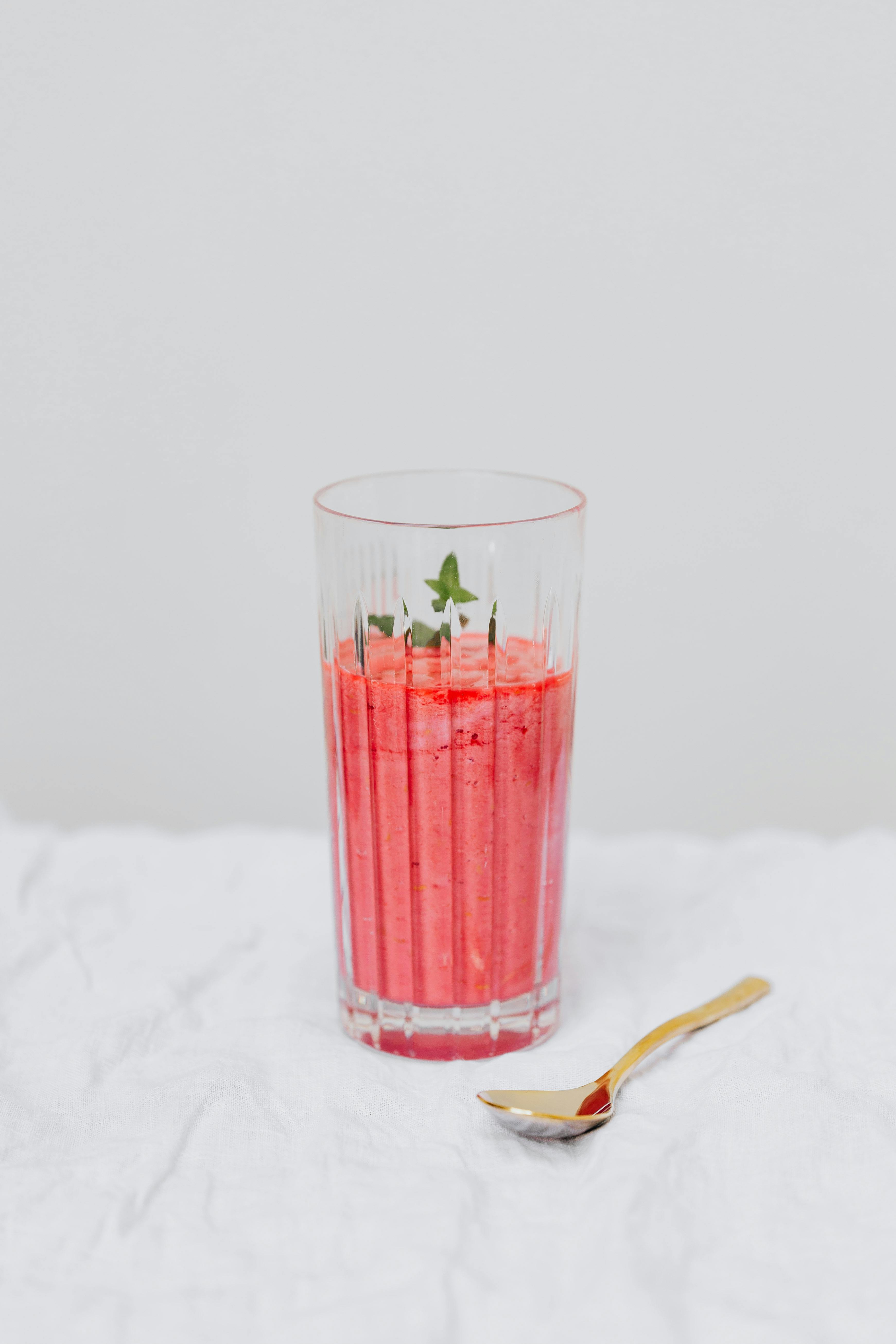 玻璃杯中盛着充满活力、新鲜的草莓冰沙，配以薄荷装饰和金勺