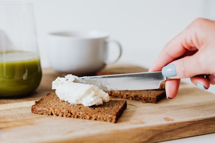 Hand Spreading The White Cream On The Bread 