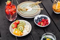 户外餐桌上摆放着新鲜的草莓、猕猴桃、浆果和鸡尾酒