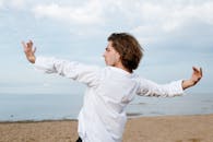 一位男舞者在海滩上，以海洋为背景，表演着富有表现力的当代舞蹈动作