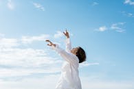 在晴朗的蓝天下，一位穿着白衬衫的男子优雅地跳舞