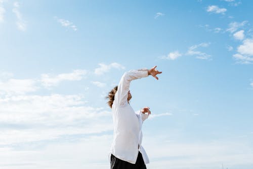 Woman in White Long Sleeve Shirt and Black Skirt Standing on White Clouds