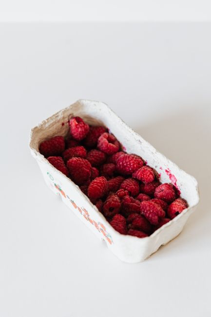 Delicious raspberries in a biodegradable container, captured in a bright and fresh setting.