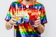 特写镜头中，一位女士手持两杯装饰着新鲜水果的五彩鸡尾酒
