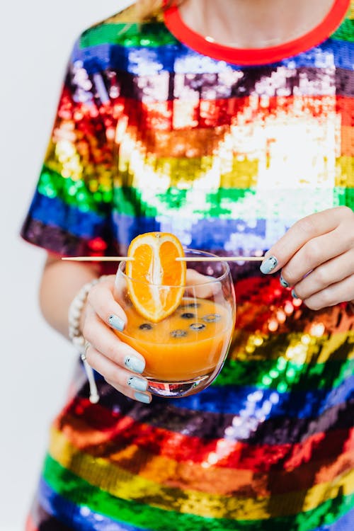 Person Holding Clear Drinking Glass With Orange Fruit