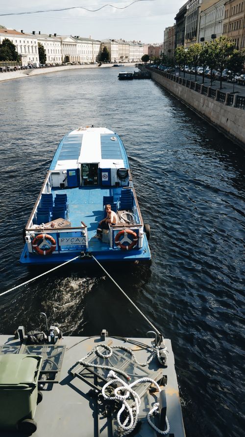 Free From above of cruise boat sailing on canal between typical aged building on sunny day Stock Photo