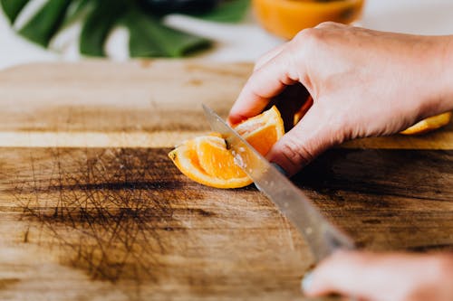 Free Person Holding Stainless Steel Knife and Sliced Orange Fruit Stock Photo