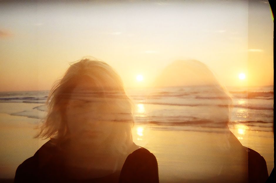 A creative double exposure image featuring a woman's silhouette against a vibrant Brazilian sunset on the beach.