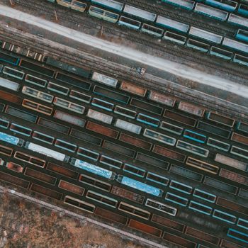 Drone shot of colorful cargo trains lined up in a rail yard, showcasing industrial logistics.