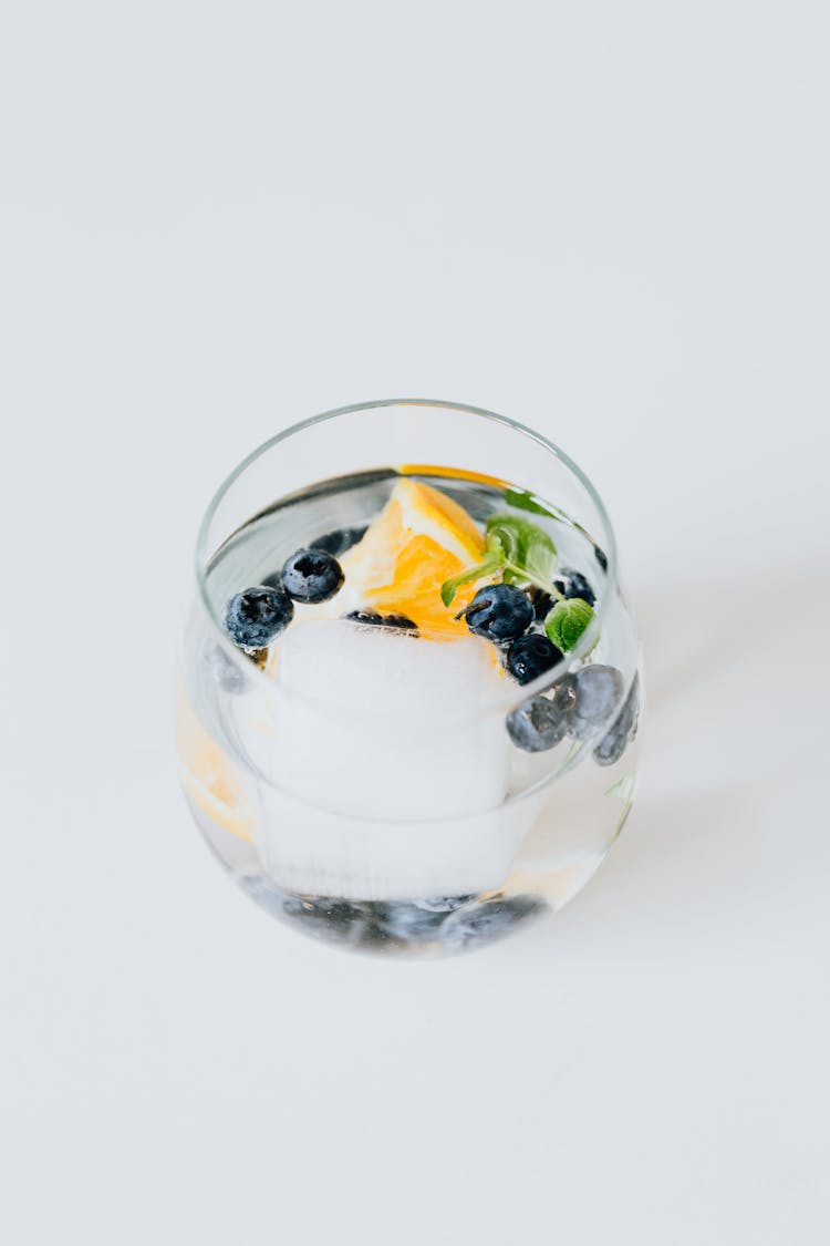 A Glass Of Water With Blueberries, Mint Leaves And A Slice Of Orange Fruit